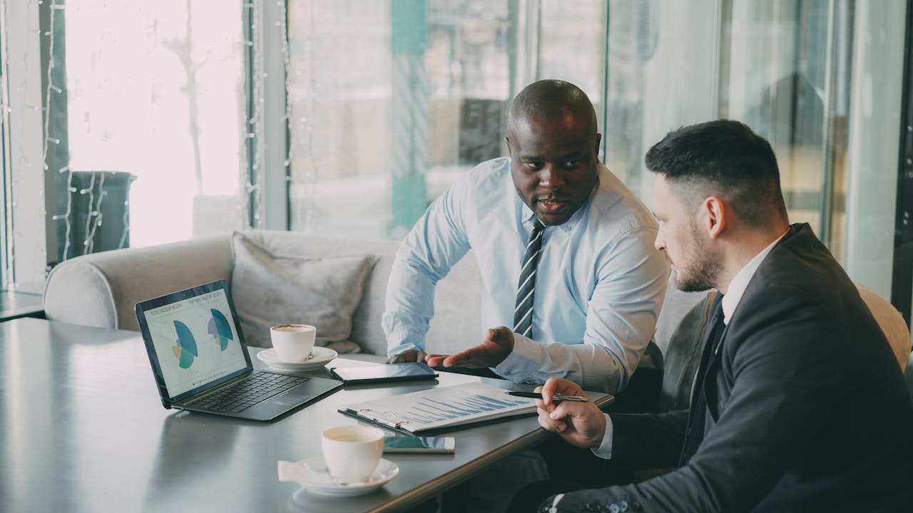 Two businessmen discussing data at a cafe while enjoying coffee.